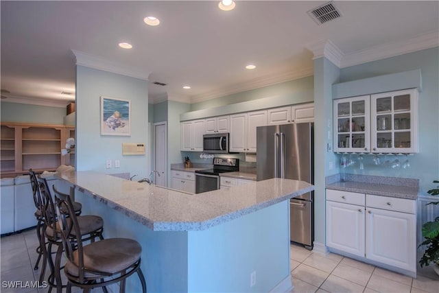 kitchen featuring a breakfast bar, white cabinetry, stainless steel appliances, light stone counters, and kitchen peninsula