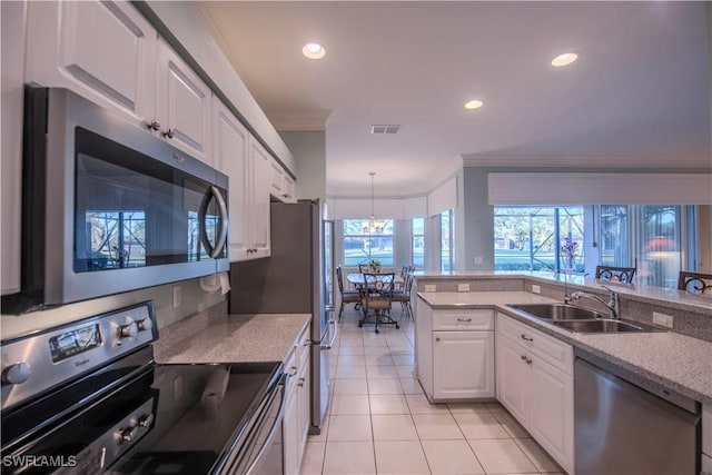 kitchen with sink, white cabinetry, ornamental molding, appliances with stainless steel finishes, and light stone countertops