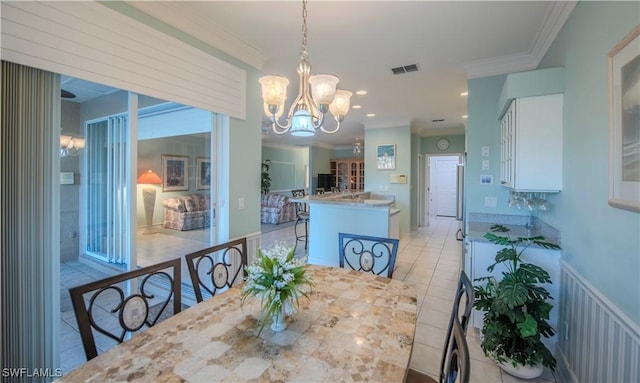 tiled dining room featuring crown molding and a chandelier