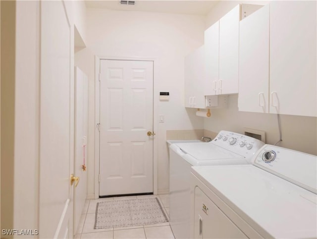 clothes washing area with cabinets, light tile patterned floors, and independent washer and dryer