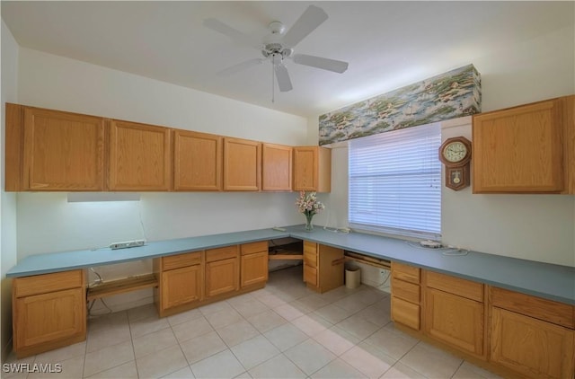 unfurnished office featuring ceiling fan, built in desk, and light tile patterned floors