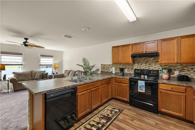 kitchen with sink, light wood-type flooring, black appliances, kitchen peninsula, and decorative backsplash