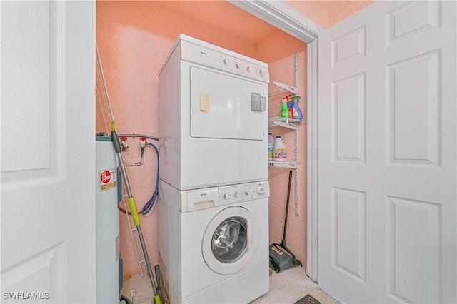 washroom featuring electric water heater and stacked washer / dryer