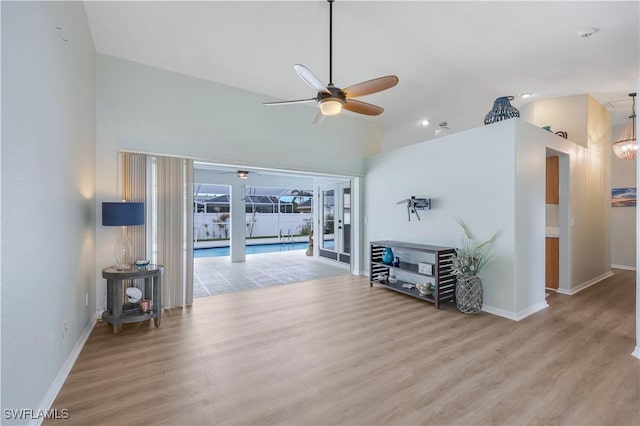 living room with high vaulted ceiling, ceiling fan, and light wood-type flooring