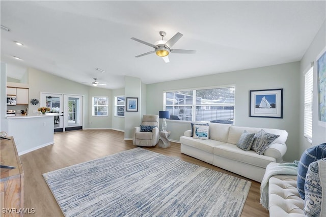 living room featuring french doors, lofted ceiling, a healthy amount of sunlight, and light wood-type flooring