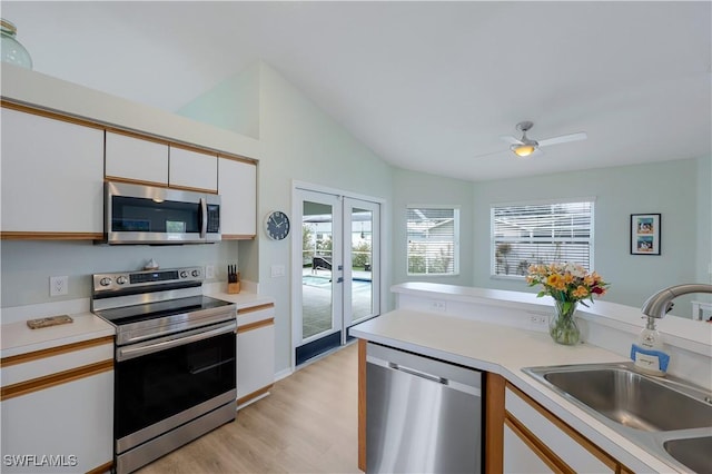 kitchen with white cabinetry, sink, light hardwood / wood-style floors, stainless steel appliances, and french doors