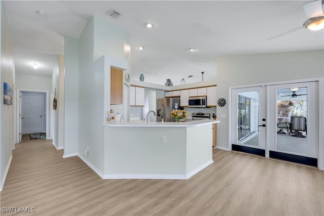 kitchen with ceiling fan, appliances with stainless steel finishes, vaulted ceiling, and light hardwood / wood-style flooring