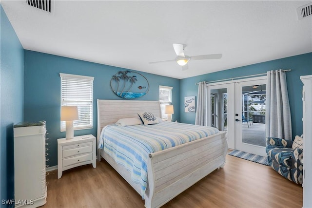 bedroom with multiple windows, access to outside, light hardwood / wood-style floors, and french doors