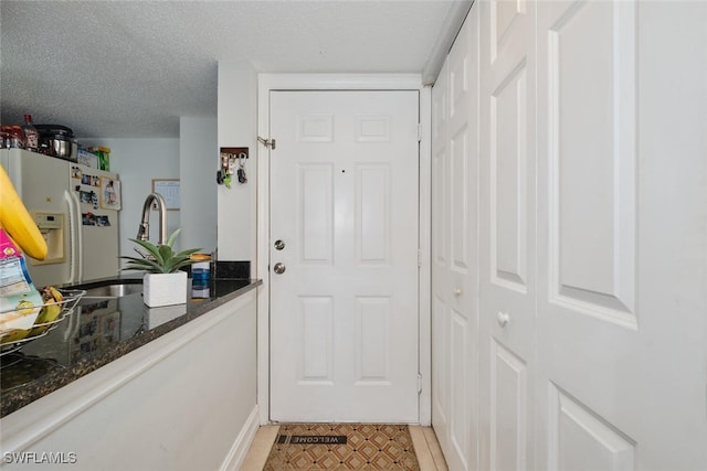 doorway with light tile patterned floors and a textured ceiling