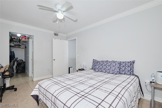 tiled bedroom featuring crown molding, a walk in closet, a textured ceiling, a closet, and ceiling fan