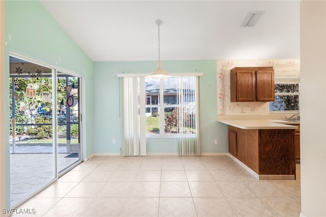 unfurnished dining area featuring vaulted ceiling, sink, and light tile patterned floors