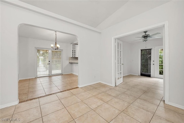 tiled empty room with lofted ceiling, ceiling fan with notable chandelier, and french doors