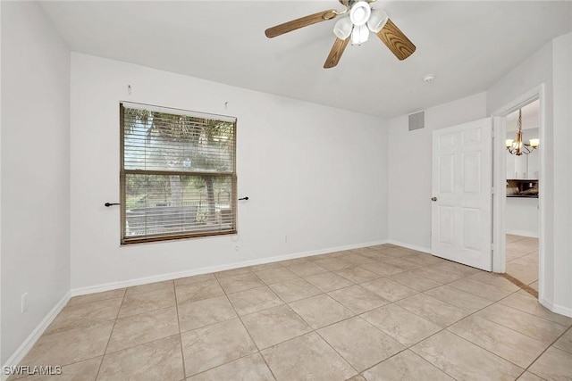 tiled spare room with ceiling fan with notable chandelier