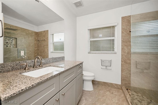 bathroom with vanity, toilet, and a tile shower