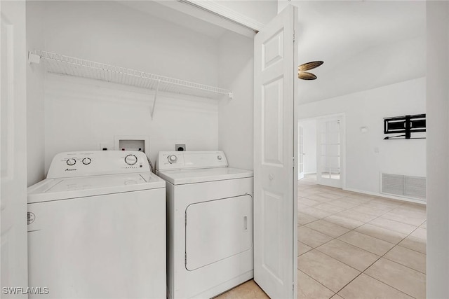 clothes washing area with light tile patterned floors and washer and dryer