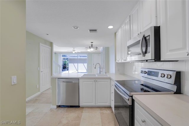 kitchen with sink, kitchen peninsula, stainless steel appliances, decorative backsplash, and white cabinets