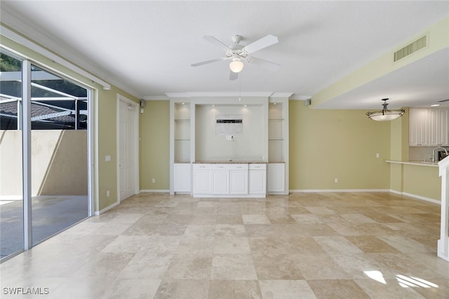 unfurnished living room with sink, crown molding, and ceiling fan