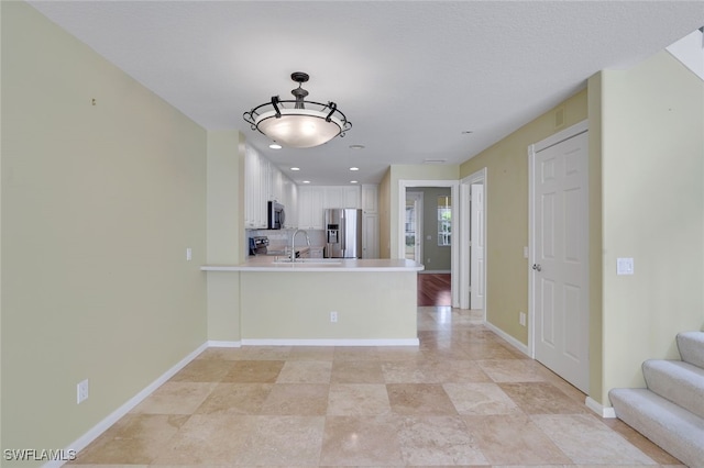 kitchen with sink, stainless steel appliances, tasteful backsplash, white cabinets, and kitchen peninsula