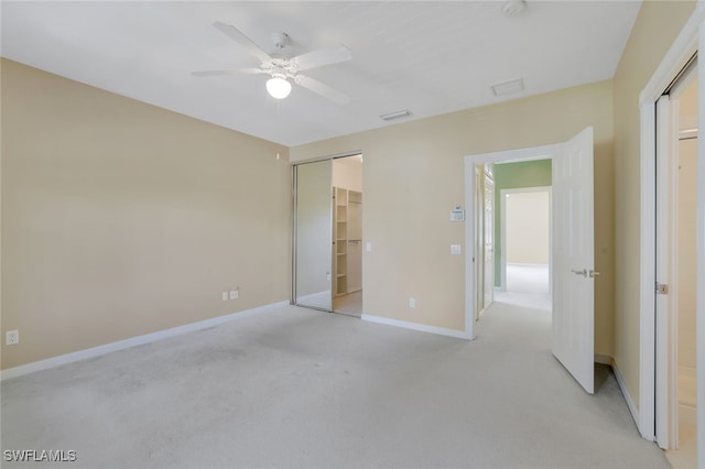 unfurnished bedroom with light colored carpet, a closet, and ceiling fan