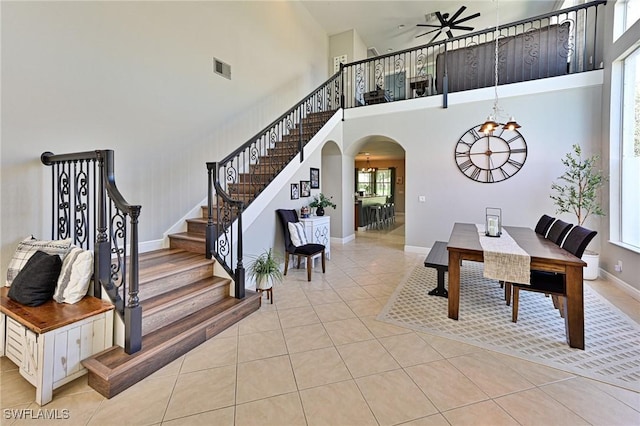 dining area featuring a towering ceiling, ceiling fan with notable chandelier, and light tile patterned flooring