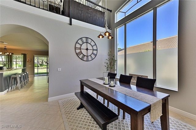 dining room featuring a towering ceiling, light tile patterned floors, and a notable chandelier