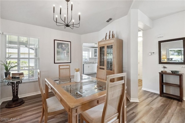 dining space featuring hardwood / wood-style flooring, a healthy amount of sunlight, and an inviting chandelier