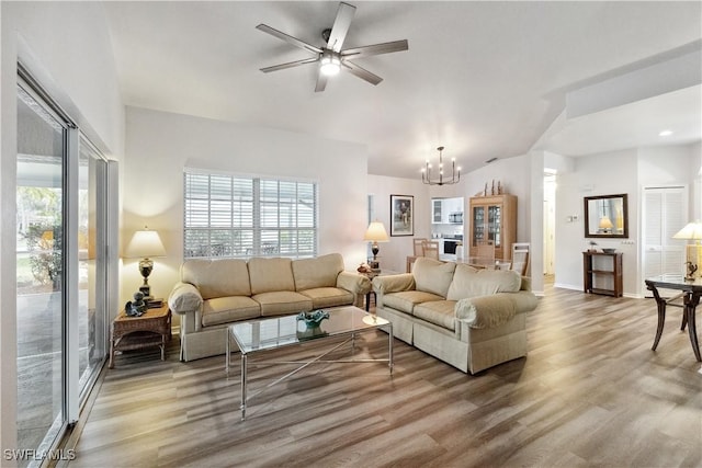 living room with ceiling fan with notable chandelier and wood-type flooring