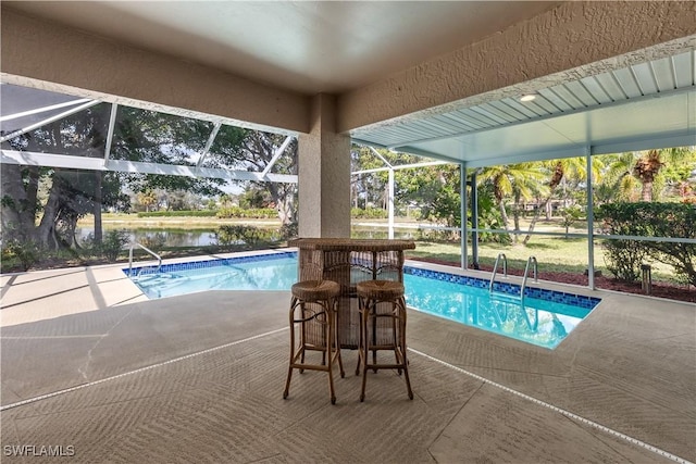 view of swimming pool featuring a water view, a patio area, and glass enclosure