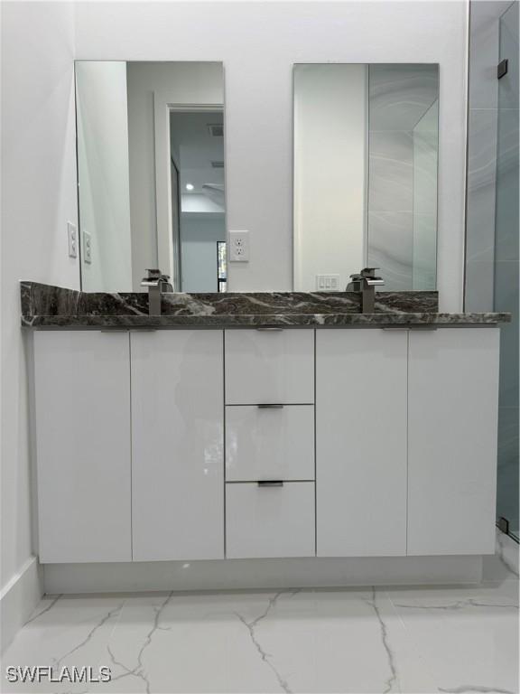 full bathroom with double vanity, a shower, marble finish floor, and a sink