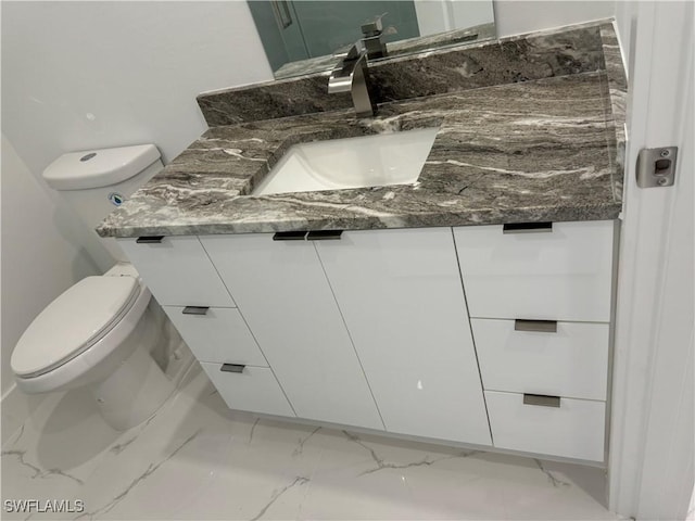 half bathroom featuring vanity, toilet, and marble finish floor