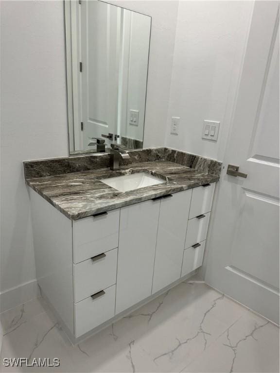 bathroom with marble finish floor, vanity, and baseboards