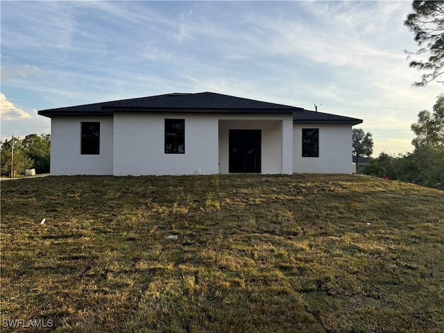 back of house with a yard and stucco siding