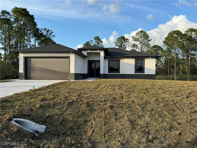 prairie-style home featuring a garage, concrete driveway, a front yard, and stucco siding