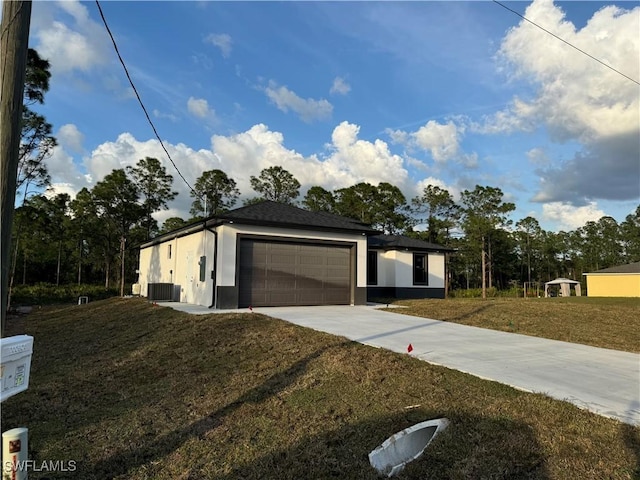 view of front of home with stucco siding, a front lawn, an attached garage, and driveway