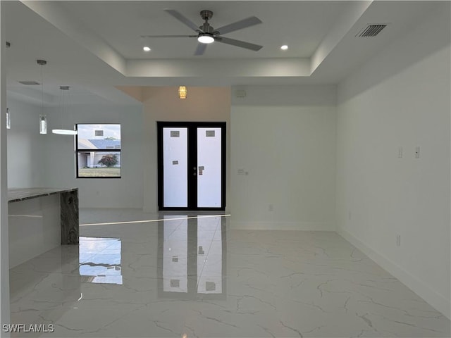 empty room featuring ceiling fan, french doors, and a raised ceiling