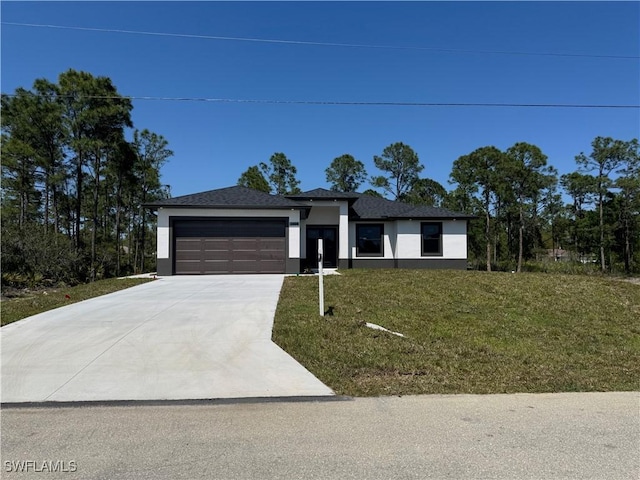 prairie-style house with stucco siding, concrete driveway, a garage, and a front yard