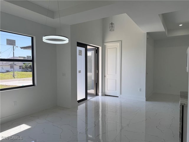 empty room with recessed lighting, marble finish floor, baseboards, and a tray ceiling