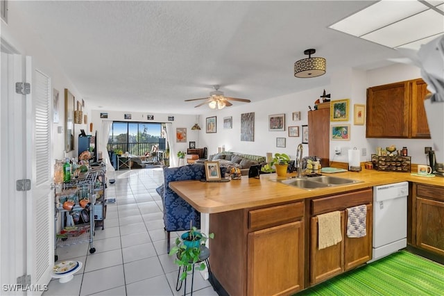 kitchen featuring sink, light tile patterned floors, white dishwasher, kitchen peninsula, and ceiling fan