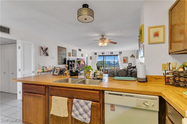 kitchen featuring sink, butcher block counters, light tile patterned floors, ceiling fan, and white dishwasher