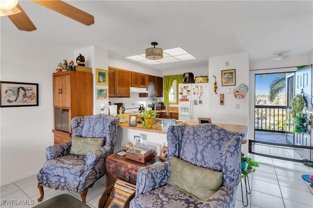 living room featuring ceiling fan, a textured ceiling, and light tile patterned floors