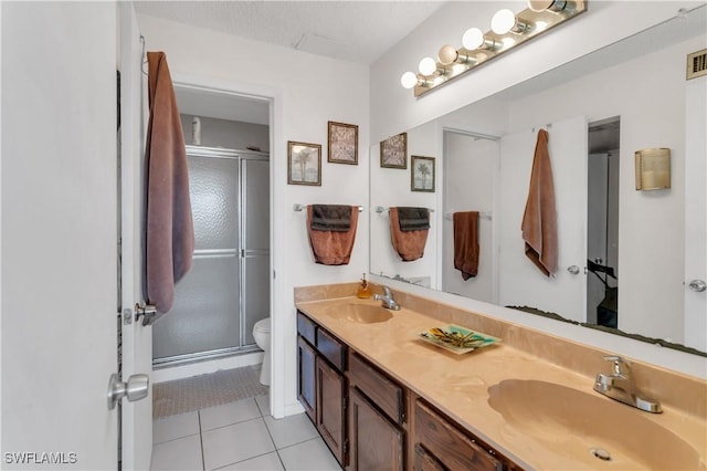 bathroom featuring vanity, a shower with shower door, tile patterned floors, and toilet