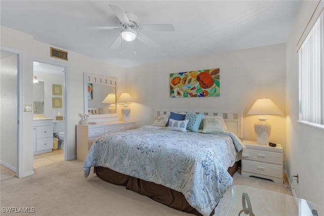 bedroom featuring ceiling fan, ensuite bath, and light carpet