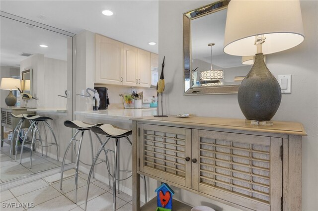 kitchen featuring pendant lighting, light tile patterned floors, tasteful backsplash, and a breakfast bar