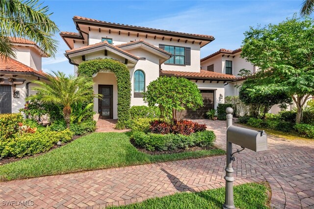 mediterranean / spanish-style home with a tiled roof, decorative driveway, a garage, and stucco siding