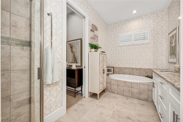 bathroom featuring vanity, tile walls, and plus walk in shower