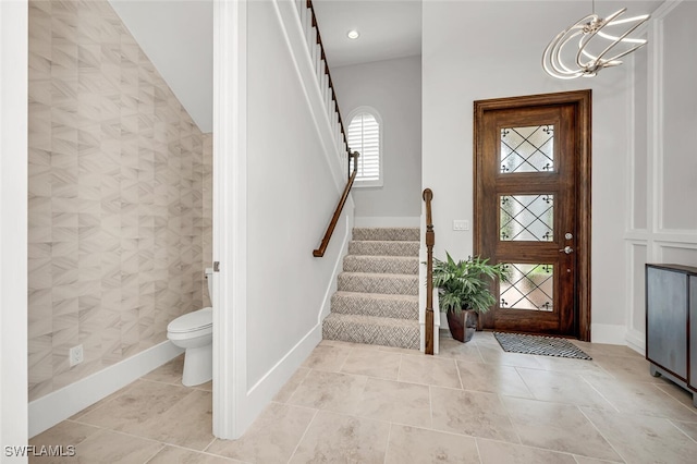 entrance foyer with light tile patterned floors, stairs, and baseboards