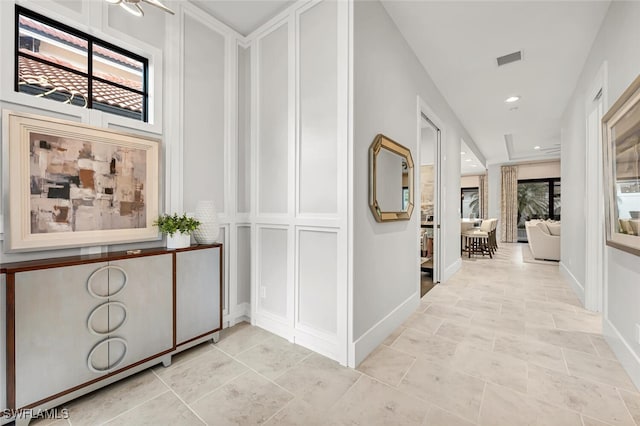 hall featuring a wealth of natural light, visible vents, and baseboards