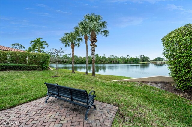 surrounding community with a water view, a patio area, and a lawn