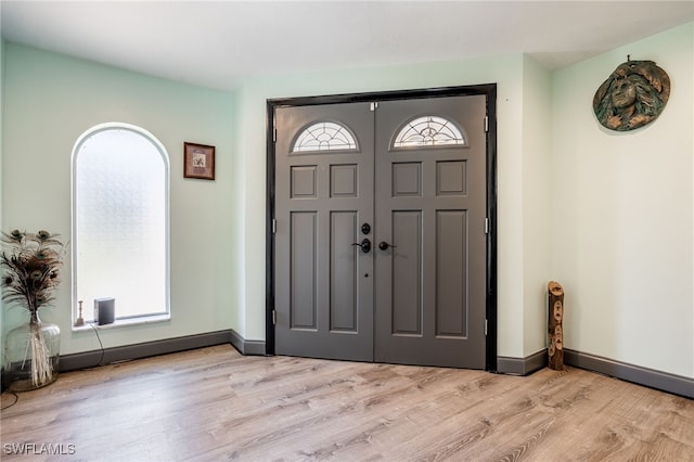 foyer entrance with light wood-style floors and baseboards