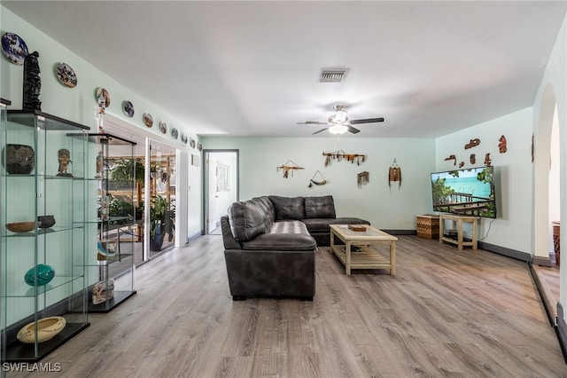 living area featuring a ceiling fan, visible vents, baseboards, and wood finished floors